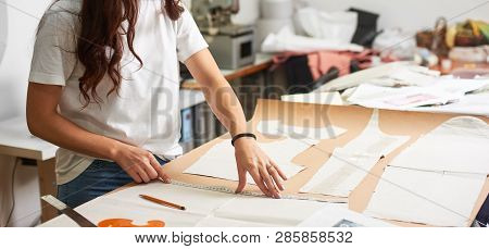 Workplace In Design Studio. Professional Female Designer Making Paper Patterns Using Measuring Tape,