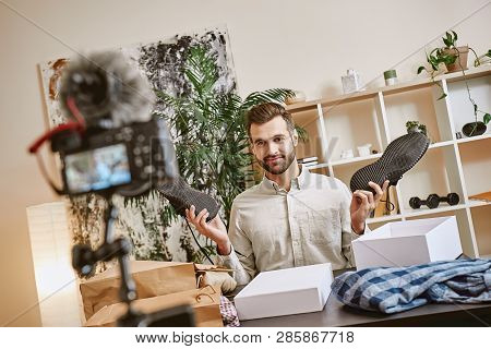 Fashion Advice. Smiling Male Fashion Blogger Showing Sport Shoes On Camera While Recording New Video