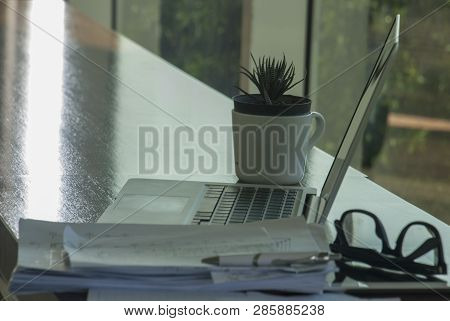 Work Area With Laptops And Communication Devices, Including Work Documents And Glasses And Small Pot