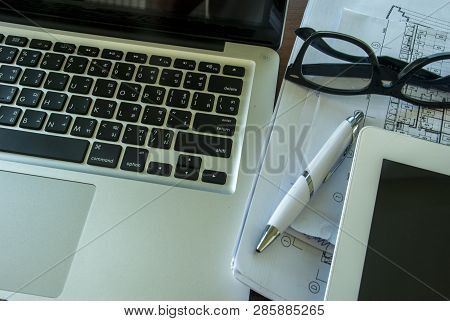 Top View Of The Table With Laptops And Tablets, Including Glasses, Notebooks, Pens And Work Document