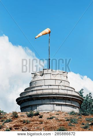 Windsock On The Stone Tower Shows Wind Direction. Teal And Orange Photo Filter.