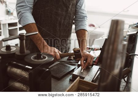 Important Stage In The Work. Male Goldsmith Wearing Apron Making A New Product At A Workbench Using 