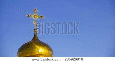 Gilded Orthodox Cross On The Dome Of The Church Against The Blue Sky