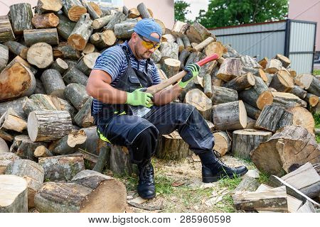 Muscular Young Man Chopping Logs. Heavy Physical Labor.