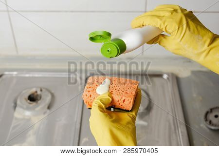 Two Hands Applying Liquid Soap From Cleanser Bottle To Orange Sponge. Extruding Detergent Onto Orang