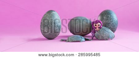 Three Gray, Blue Easter Eggs, Like Stones. Two Toy Mermaids. Lilac Background