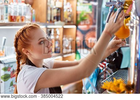 Female Bartender Tapping Craft Beer In Bar, Side View Of Red Haired Barman Wearing White Casual T Sh