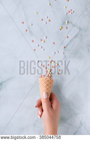 Creative Flat Lay With Sugar Ice Particles Coming Out Of Ice Cream Waffle Cone On Marble Table.