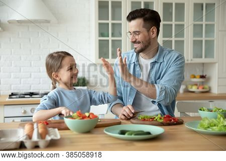 Small Girl Giving High Five To Loving Father In Kitchen.