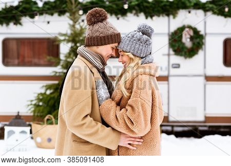 Happy Young Couple Hugging And Laughing Outdoors In Winter, Standing Near Rv Trailer Motorhome At Ca