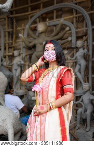 Portrait Of Beautiful Indian Girl Standing In Front Of Durga Idol Wearing Traditional Indian Saree, 