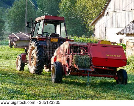 Zetea, Romania- 13 September 2020: Old Tractor Equipped With Welger Baling Press In The Early Hours.