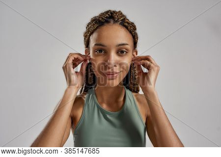Portrait Of Young African Fitness Woman Wearing Wireless Earbuds, Looking At Camera And Smiling Whil