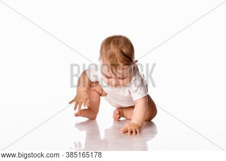 Little Baby Examines His Reflection On The White Floor In The Studio Against The White Wall. Child D