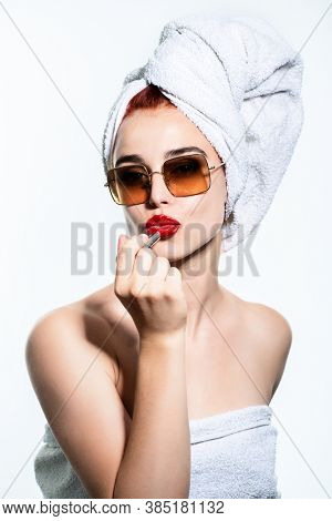 Fashion blogger at the morning. Young glam pretty woman with towel and sun glasses makes make-up with red lipstick looking at camear like at mirror