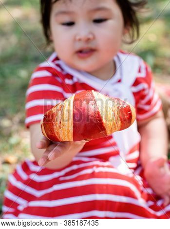 Cute Little Baby In A Red Dress And Srtaw Hat On A Picnic In The Park