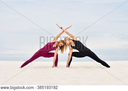 Two Beautiful Young Women Performing Together Yoga Pose Parshvakonasana