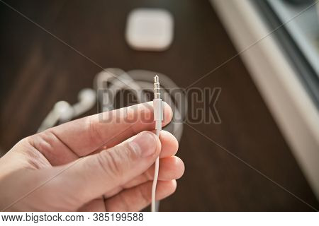 Man Hand Holds A 3.5mm Mini Jack Connector. White Headphone Jack Socket