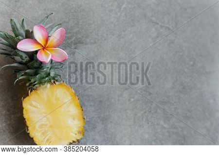 Pineapple And Frangipania On A Stone Table. Tropical Fruits. Top View. Free Space For Your Text.