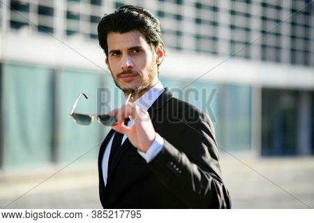 Young businessman outdoor holoding his sunglasses