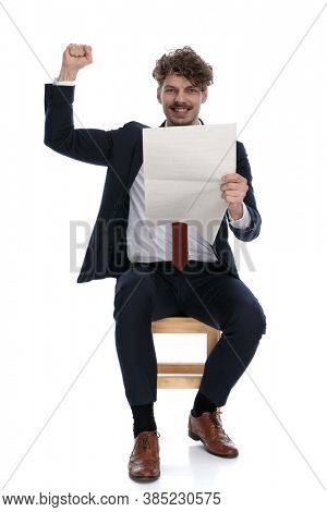 handsome excited businessman holding the newspapaer and celebrating succes, sitting on white background