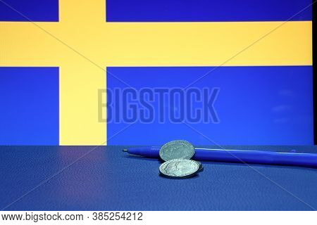 Heap Of Sweden Coins With Blue Pen On The Black Floor And Swedish Nation Flag Background,, Swedish K