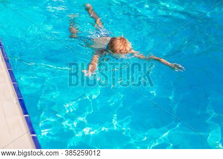 Cute Happy Little Boy In Goggles Swimming In The Swimming Pool