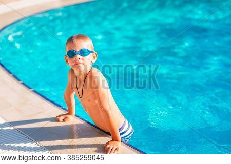 Cute Happy Little Boy In Goggles Swimming In The Swimming Pool