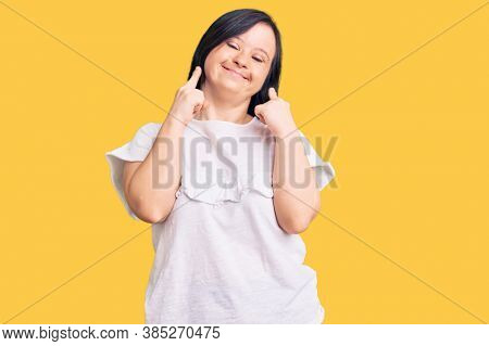 Brunette woman with down syndrome wearing casual white tshirt smiling with open mouth, fingers pointing and forcing cheerful smile 