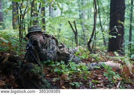 modern warfare soldier in action aiming at weapon  laser sight optics  in combat position while searching for a target in battle