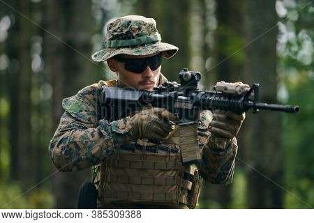 modern warfare soldier in action aiming at weapon  laser sight optics  in combat position while searching for a target in battle