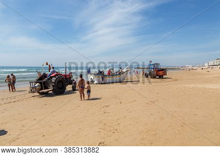 Costa Da Caparica, Portugal - September 10, 2020: An Artel Of Fishermen Trawls Fish From The Tourist