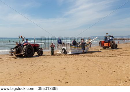 Costa Da Caparica, Portugal - September 10, 2020: An Artel Of Fishermen Trawls Fish From The Tourist