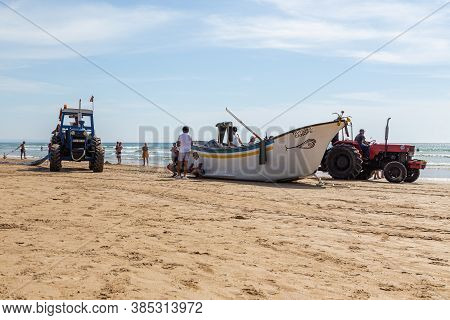 Costa Da Caparica, Portugal - September 10, 2020: An Artel Of Fishermen Trawls Fish From The Tourist