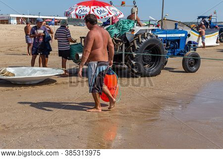 Costa Da Caparica, Portugal - September 10, 2020: An Artel Of Fishermen Trawls Fish From The Tourist