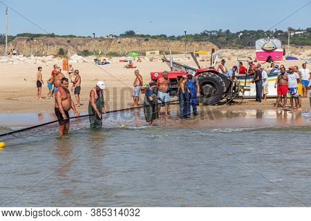 Costa Da Caparica, Portugal - September 10, 2020: An Artel Of Fishermen Trawls Fish From The Tourist