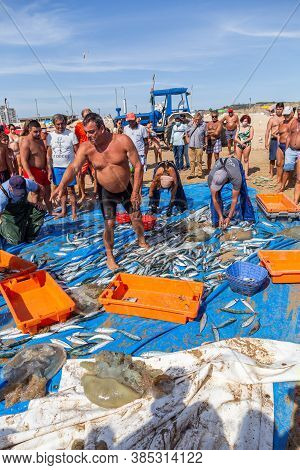 Costa Da Caparica, Portugal - September 10, 2020: An Artel Of Fishermen Trawls Fish From The Tourist