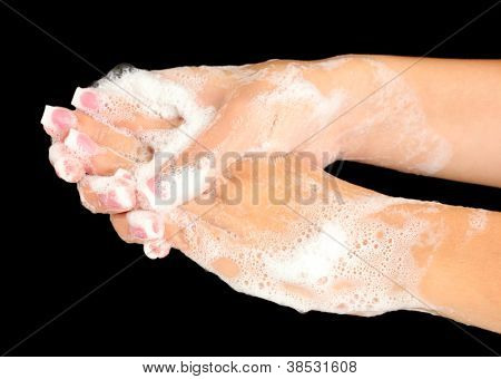 ผู้หญิงมือใน soapsuds บนพื้นหลังสีดำอย่างใกล้ชิด