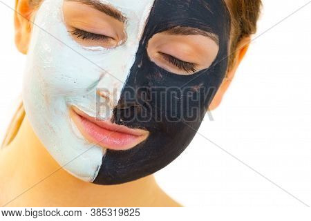 Woman With Clay Carbo Black Mask On Half Face And White Mud On Second Half. Girl Taking Care Of Oily