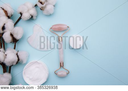 Pink Roller Face Massager And Gouache Scraper On Blue Table. Anti Age, Lifting And Toning Treatment 