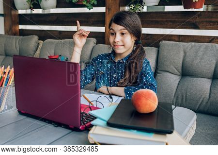 Smiling Little Schoolgirl Doing Her Homework In Front Of A Laptop, She Was Able To Solve The Task . 
