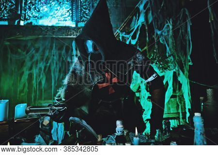 The plague doctor is working at his desk, inventing a cure for bubonic plague. The atmosphere of mysticism. Historical reenactment. Halloween. 