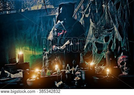 The plague doctor is working at his desk, inventing a cure for bubonic plague. The atmosphere of mysticism. Historical reenactment. Halloween. 