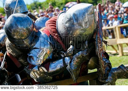 Knight Tournament. Medieval Restorers Fight With Swords In Armor At A Knightly Tournament