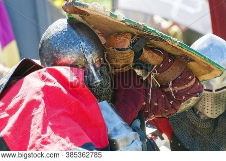 Knight Tournament. Medieval Restorers Fight With Swords In Armor At A Knightly Tournament