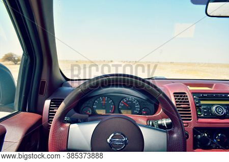 View From Inside A Nissan Car On A Part Of Dashboard And Blurred Desert Road. Steering Wheel. Muscat