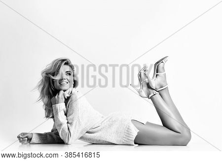 Young Sexy Smiling Woman Model In Sweater And High Heel Shoes Lying On Floor And Looking Up Over Whi