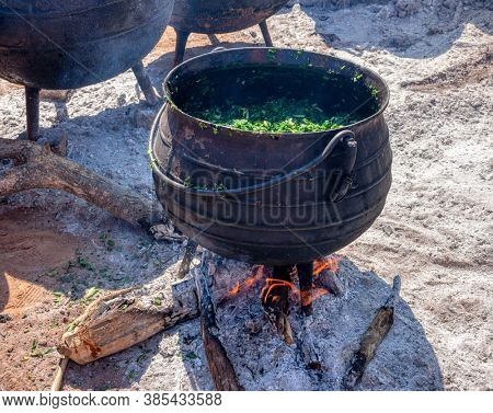 African cooking outdoors, spinach in a cast iron pot