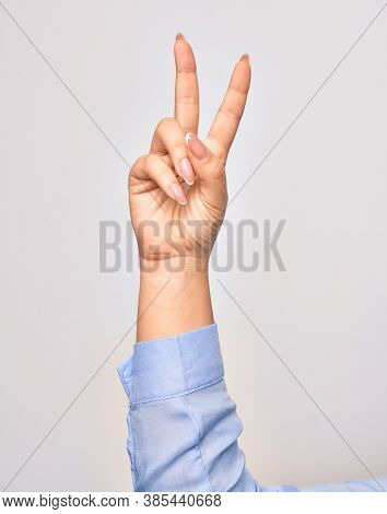 Hand of caucasian young woman doing victory symbol showing number two with streched fingers raised up over isolated white background