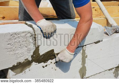 A Building Contractor Is Constructing A Wall From Autoclaved Aerated Concrete Blocks Using A Trowel 